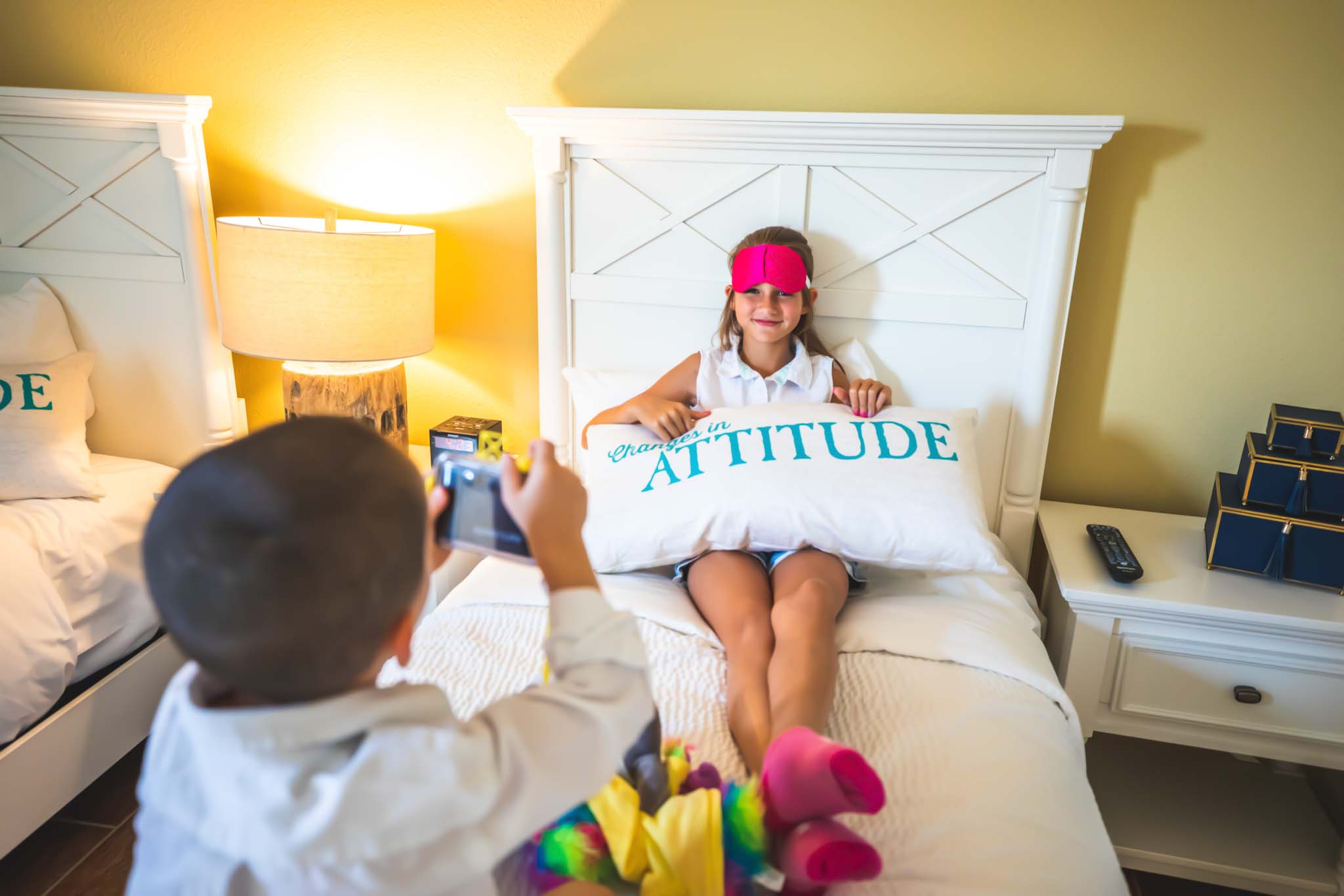Chill at Home 1 Young girl holding a Margaritaville Resort Orlando throw pillow while sitting on a hotel suite bed.